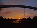 Zapadající Slunce pod obloukem mostu nad plavebním kanálem Odry kolem města Brzeg.