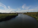 Pravobřežní živé rameno řeky Dziwna pohledem po proudu míří ke spojení s hlavním tokem řeky a dále pod větší silniční most.