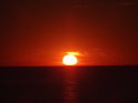 Žlutá přechází v oranžovou a zapadající Slunce barví něžná oblaka nad hladinou Baltského moře u obce Wisełka.