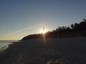 Kůl ještě brání Slunci zcela osvětlit písečnou pláž na břehu Baltského moře, ale tento stav se nedá udržet.