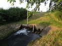 Kanalizační spojnice protéká pod pravobřežní hrází Odry nedaleko rybníka Osadnik.