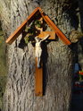 Malý křížek s Ježíšem, přibitý na na kmeni stromu u Panny Marie ve skále.
